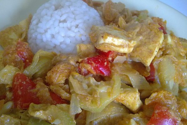 Bowl of vegetable curry with tofu next to white rice