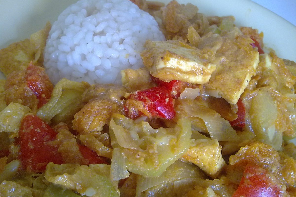 Bowl of vegetable curry with tofu next to white rice
