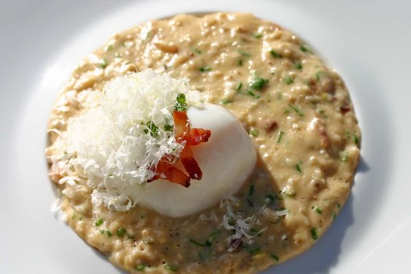 Bowl of creamy savory oats topped with an egg yolk and cheese