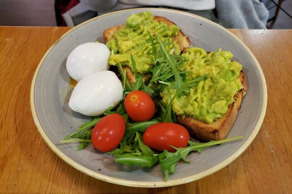 Smashed avocado toast with poached eggs and tomatoes